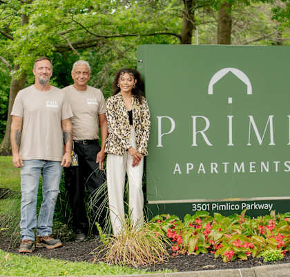 a group of people standing in front of a primes apartments sign