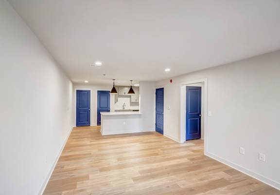 a living room and kitchen with white walls and wood flooring