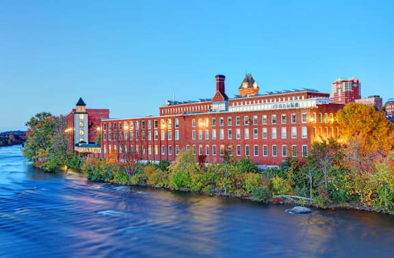A large red building sits on the bank of a river.