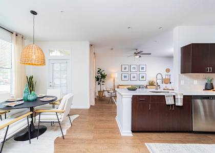 a living room and kitchen with a dining room table and chairs at Terraces at Town Center, Jacksonville, FL