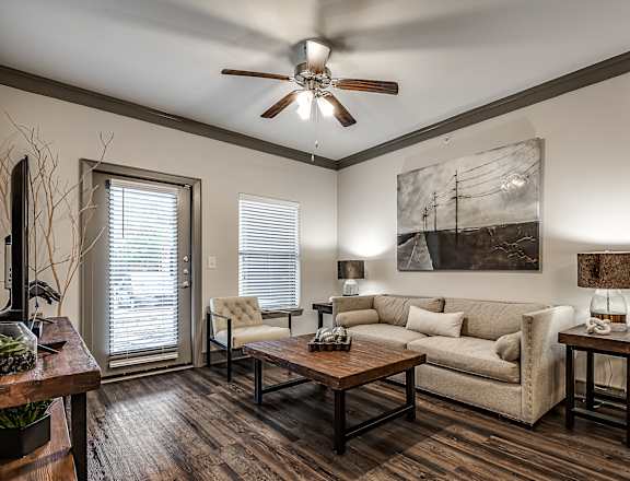 A living room with a couch, a chair, a coffee table, and a painting on the wall.