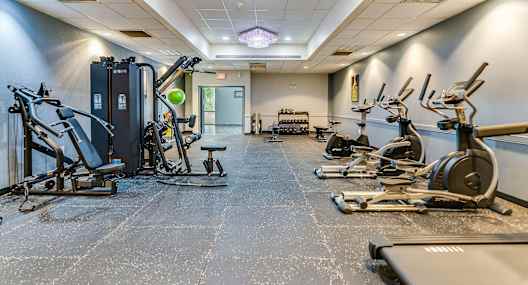 A gym with a variety of exercise equipment including treadmills, stationary bikes, and weight machines.