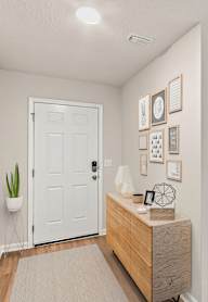 A hallway with a white door, a wooden bench, and a wall with pictures and a clock.