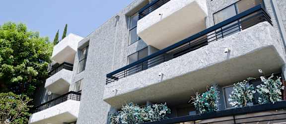 an apartment building with balconies and trees in the background