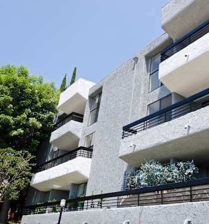 an apartment building with balconies and trees in the background