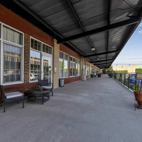 a covered porch with a fire pit and a building with windows at The Lofts at Elk Terminal Apartments , Buffalo