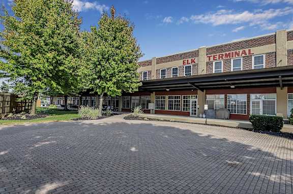 the front of a school building with a brick driveway and trees at The Lofts at Elk Terminal Apartments , Buffalo