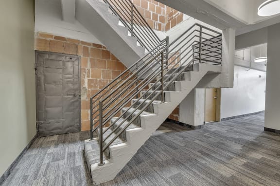 a staircase in a building with a brick wall and a metal railing at The Lofts at Elk Terminal Apartments , Buffalo