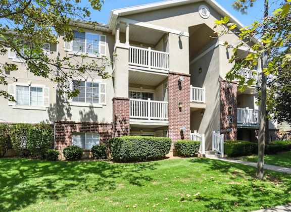 A large apartment building with a green lawn in front.at Country Oaks Apartments, Utah, 84015