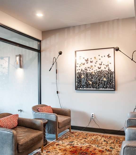 A room with grey couches and a painting on the wall.