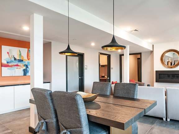 A modern dining room with a wooden table and grey chairs.