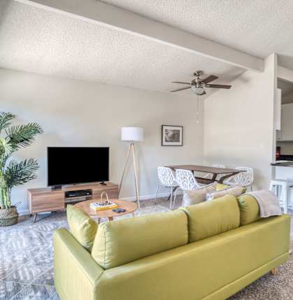 a living room with a yellow couch and a ceiling fan