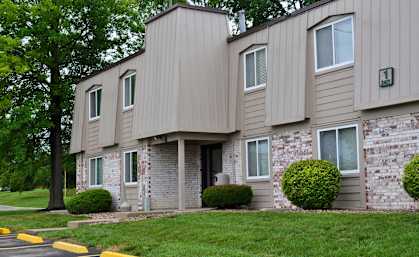 The exterior of Park 25 Apartments, featuring a well-maintained lawn with green grass and a tree near the front entrance.