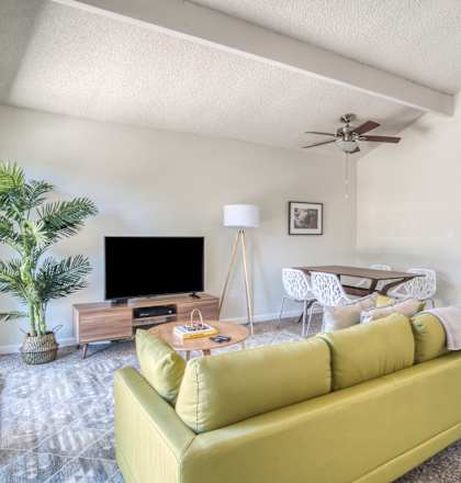 A living room with a yellow couch and a television.