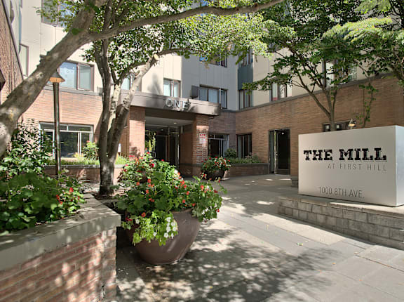 The Mill at First Hill is a modern building with a brick facade and a large entrance.