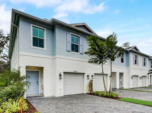 a white and blue house with palm trees in front of it
