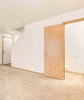 A room with a carpeted floor and two wooden doors.