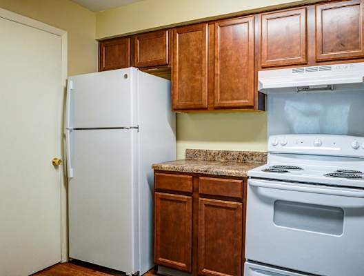 A white refrigerator stands next to a stove in a kitchen.