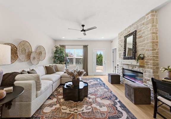 A living room with a white couch, a rug, and a fireplace.