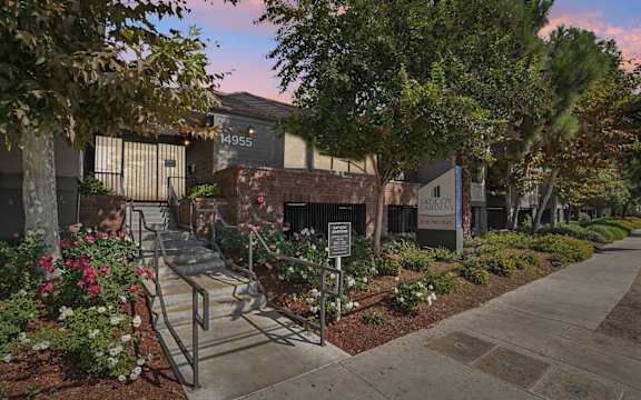 A building with the number 14955 is surrounded by a garden with a staircase leading to the entrance.