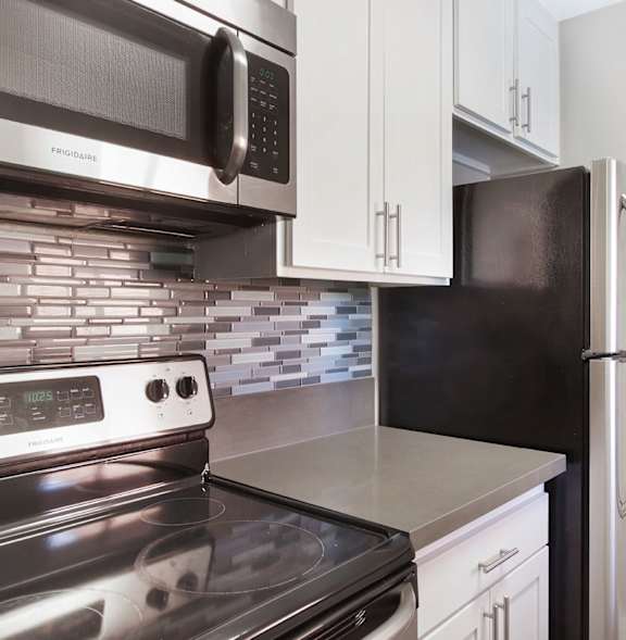 A modern kitchen with a stove, microwave, and refrigerator.