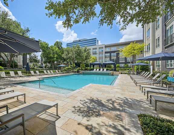 A pool surrounded by sun loungers and umbrellas.