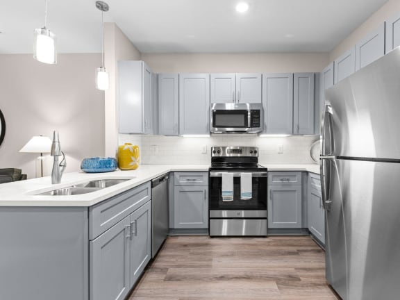 an empty kitchen with stainless steel appliances and gray cabinets