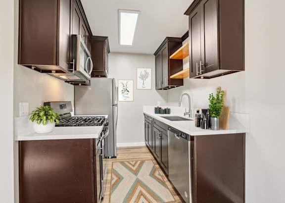 a kitchen with black cabinets and stainless steel appliances and a white counter top