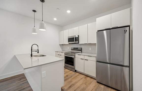 A modern kitchen with a refrigerator, sink, and oven.