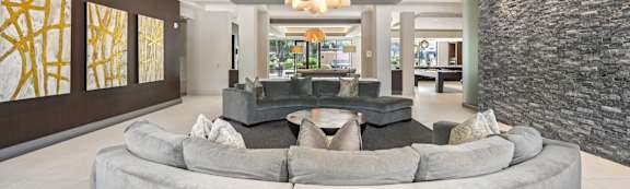 A modern living room with a stone wall and a large grey couch.