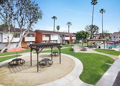 A sunny day at a park with picnic tables and benches.