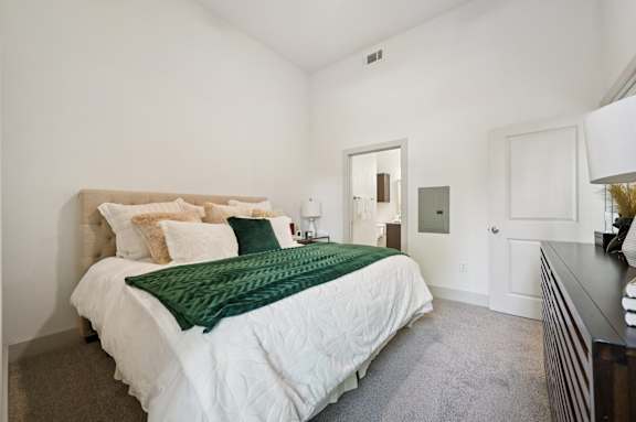 A bedroom with a large bed and a green throw blanket.