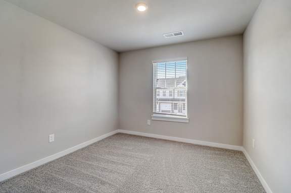 A room with a window and a carpeted floor.