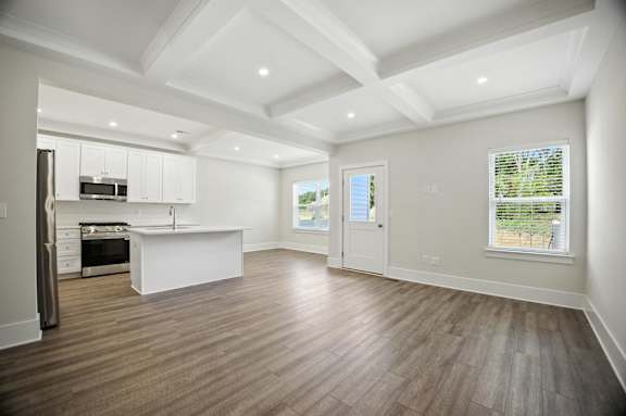A spacious kitchen with white cabinets and a wooden floor.