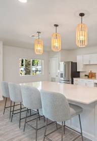 A kitchen with a white island and grey chairs.