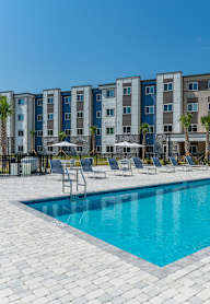 A swimming pool in front of a row of apartment buildings.