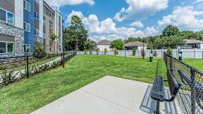 A park with a bench and a fence in front of a building.