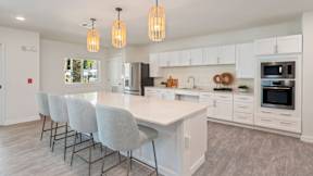A modern kitchen with a large island and grey chairs.