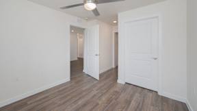 A room with a ceiling fan and wooden flooring.