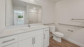 A white bathroom with a toilet, sink, and mirror.