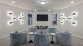 A room with grey chairs and a black television mounted on the wall.