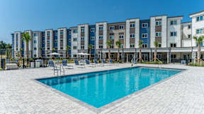 A swimming pool in front of a row of apartment buildings.