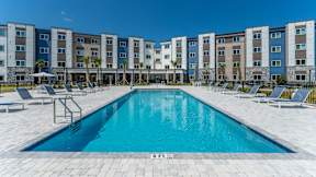 A swimming pool in front of a row of apartment buildings.