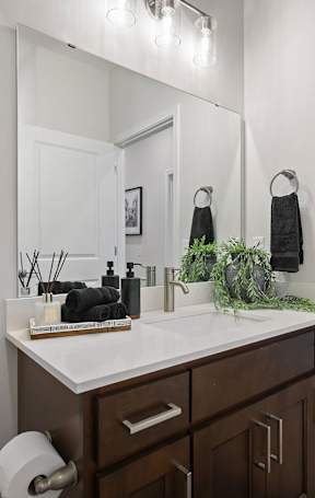 A bathroom with a white counter top and brown drawers.