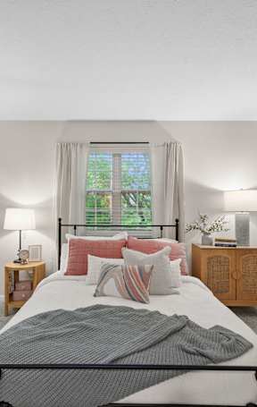 A bedroom with a bed, nightstands, and a plant.