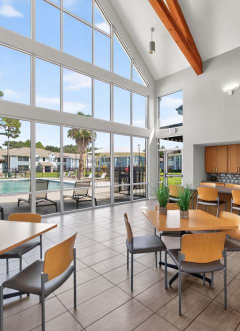 a clubhouse with tables and chairs and a kitchen with large windows at Lakecrest Village, Houston, TX 77078