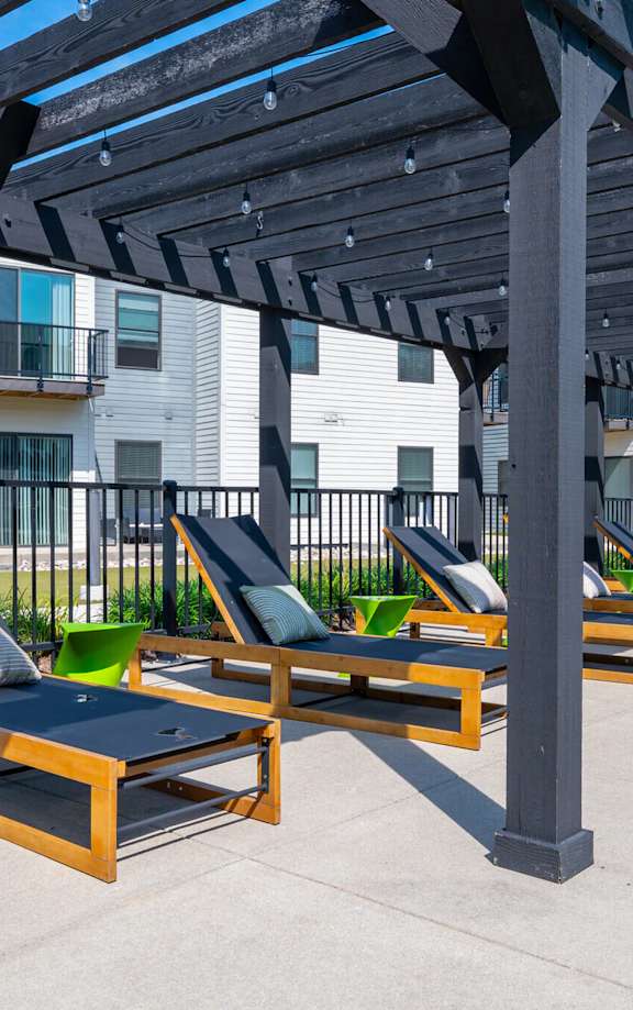 A sunny day at the outdoor lounge area with wooden sunbeds and a pergola.