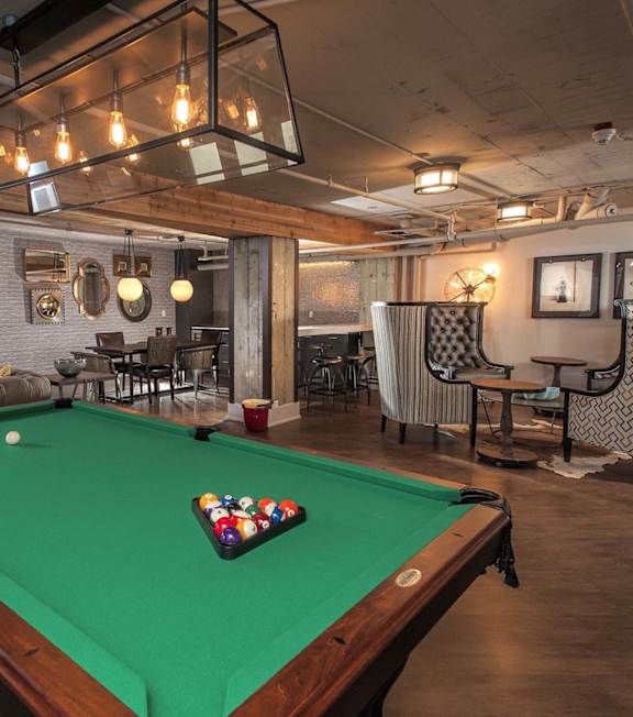 A pool table is in the middle of a room with a couch and a TV.