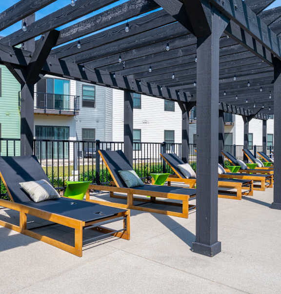A sunny day at the outdoor lounge area with wooden sunbeds and a pergola.