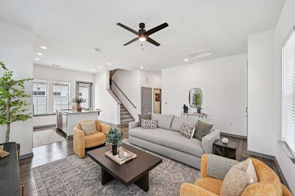 A living room with a grey couch, a brown coffee table, and a ceiling fan. at The Hadley - North Port, FL Apartments, North Port
